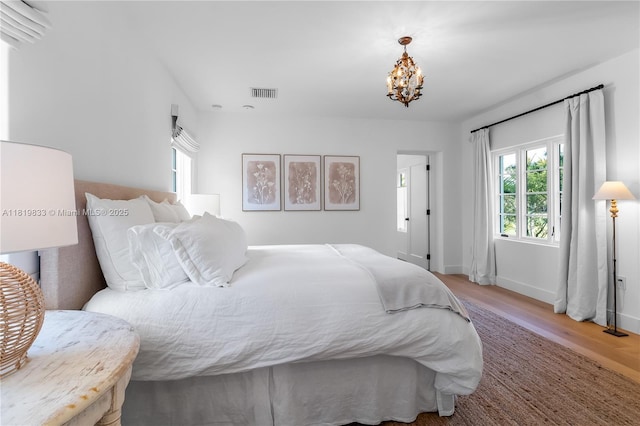bedroom with wood finished floors, a chandelier, and baseboards