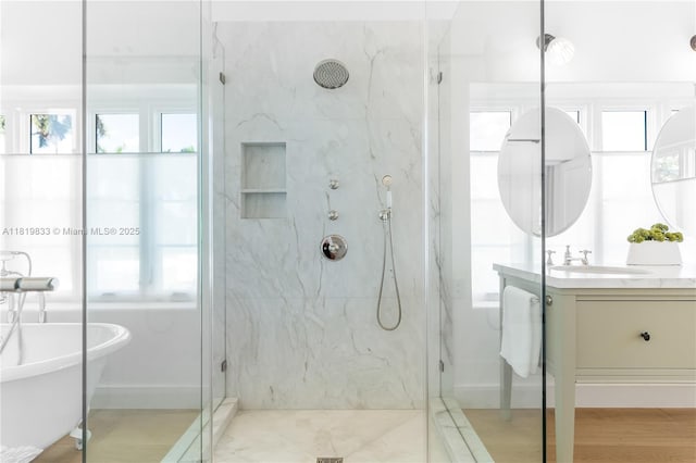 full bathroom featuring a marble finish shower, vanity, and a freestanding tub