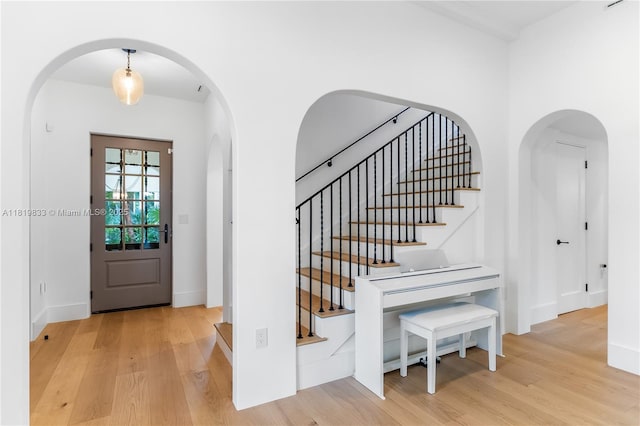 foyer entrance with wood finished floors, arched walkways, and stairway