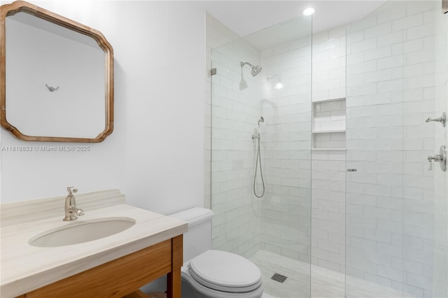 bathroom with tiled shower, vanity, and toilet