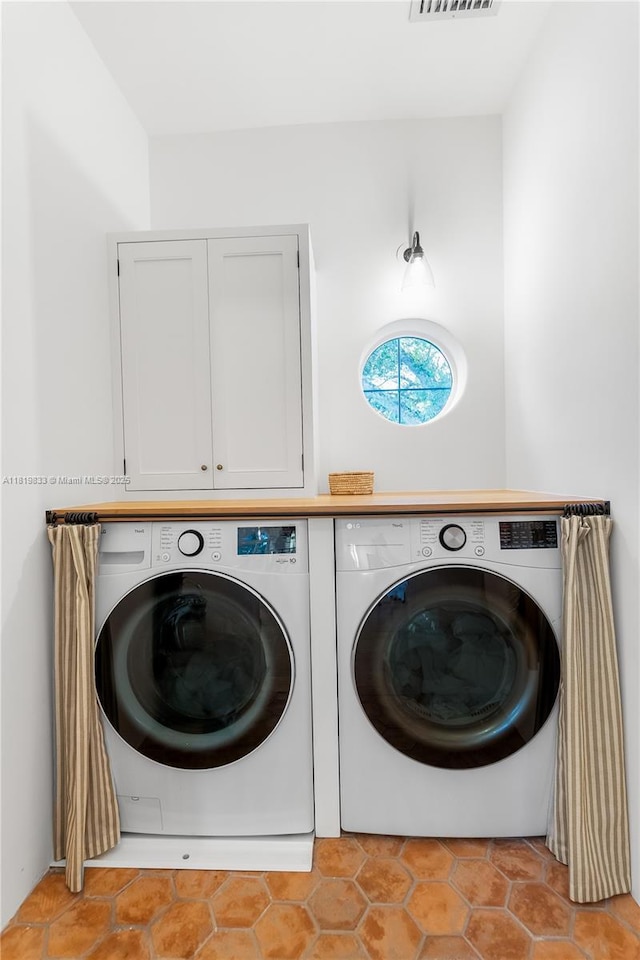 laundry room featuring independent washer and dryer, cabinet space, and light tile patterned floors