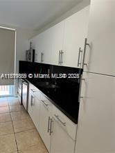 8888 Collins Ave Unit 318, Surfside, FL 33154 - kitchen with white cabinets, light tile patterned floors, and dark countertops