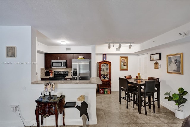 15400 SW 284th St Unit 1204, Homestead, FL 33033 - kitchen with stainless steel appliances, a peninsula, light tile patterned floors, light countertops, and rail lighting
