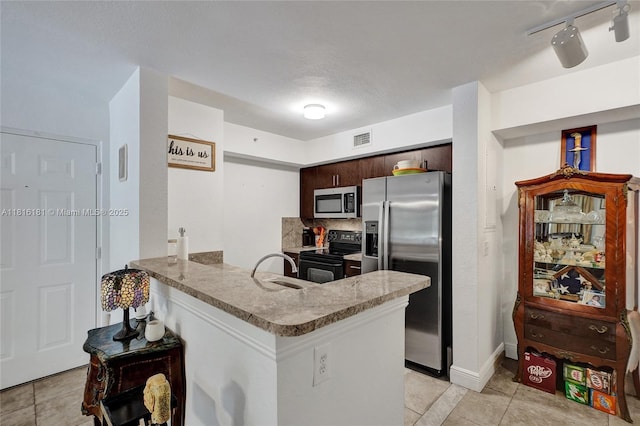 15400 SW 284th St Unit 1204, Homestead, FL 33033 - kitchen with stainless steel appliances, a peninsula, light tile patterned flooring, dark brown cabinetry, and tasteful backsplash