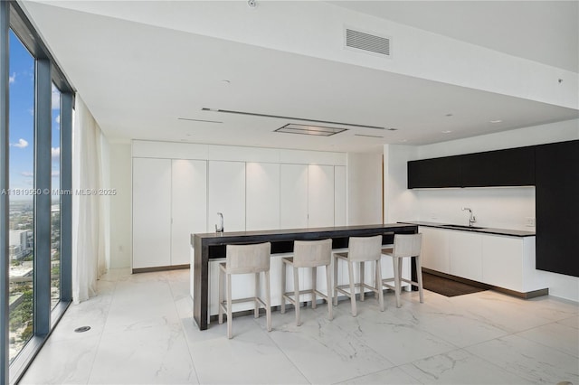 1000 Biscayne Blvd Unit 4401, Miami, FL 33132 - kitchen featuring a sink, modern cabinets, light marble finish floors, expansive windows, and white cabinets