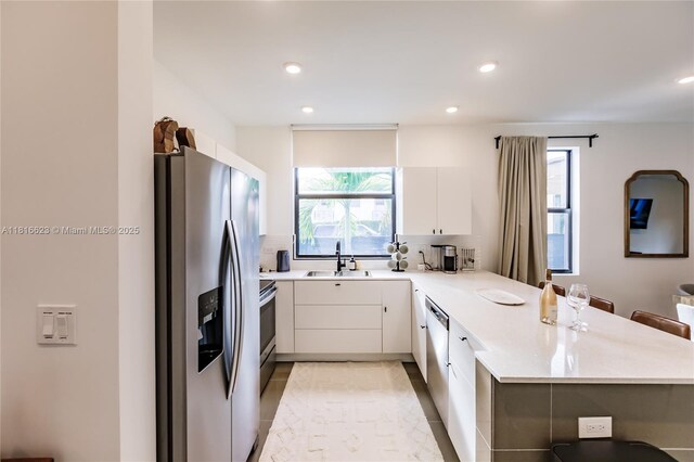 3645 SW 3rd St, Miami, FL 33135 - kitchen with appliances with stainless steel finishes, a sink, a peninsula, light countertops, and white cabinets
