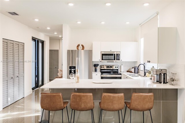 3645 SW 3rd St, Miami, FL 33135 - kitchen with stainless steel appliances, a sink, a peninsula, light countertops, and white cabinets