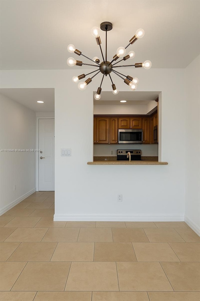 4242 NW 2nd St Unit 807, Miami, FL 33126 - kitchen with appliances with stainless steel finishes, a chandelier, light tile patterned floors, baseboards, and brown cabinets