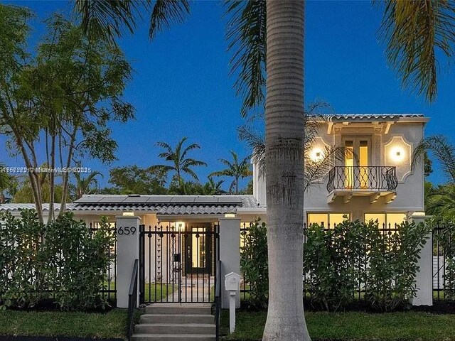659 NE 73rd St, Miami, FL 33138 - mediterranean / spanish home featuring a balcony, roof mounted solar panels, stucco siding, and a gate