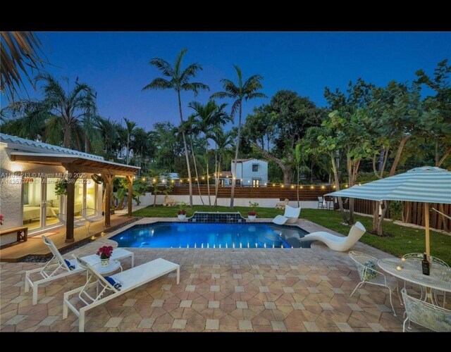 659 NE 73rd St, Miami, FL 33138 - pool at night with a fenced backyard and a patio area