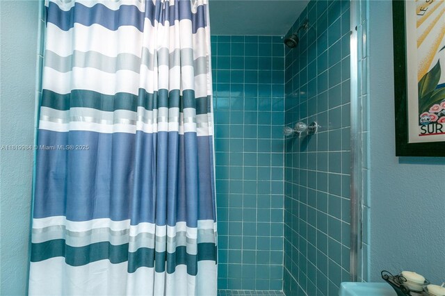 1001 NE 14th Ave Unit 107, Hallandale Beach, FL 33009 - bathroom featuring a tile shower and a textured wall