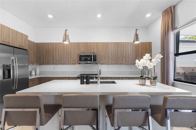 17540 SW 46th St, Miramar, FL 33029 - kitchen with modern cabinets, appliances with stainless steel finishes, brown cabinetry, light countertops, and a breakfast bar area