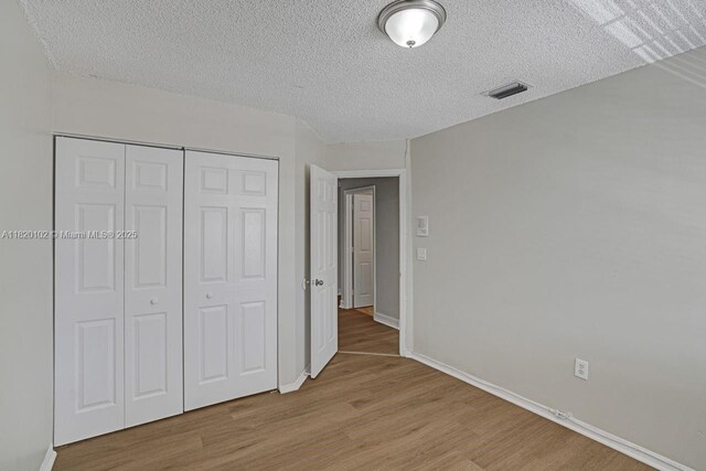 164 Granada Ave, Weston, FL 33326 - unfurnished bedroom with wood finished floors, a closet, and a textured ceiling
