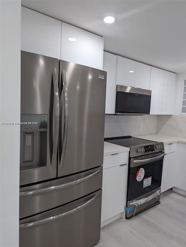 2801 NE 183rd St Unit 1709W, Aventura, FL 33160 - kitchen featuring stainless steel appliances, white cabinetry, light countertops, modern cabinets, and decorative backsplash