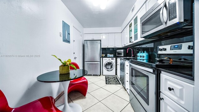 6770 Indian Creek Dr Unit 7B, Miami Beach, FL 33141 - kitchen with washer / dryer, appliances with stainless steel finishes, dark countertops, and white cabinets