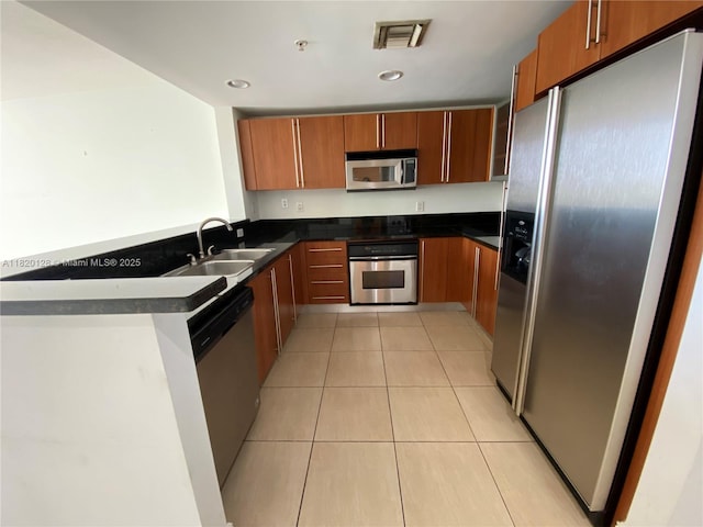 610 Clematis St Unit 721, West Palm Beach, FL 33401 - kitchen featuring stainless steel appliances, dark countertops, brown cabinets, light tile patterned flooring, and recessed lighting