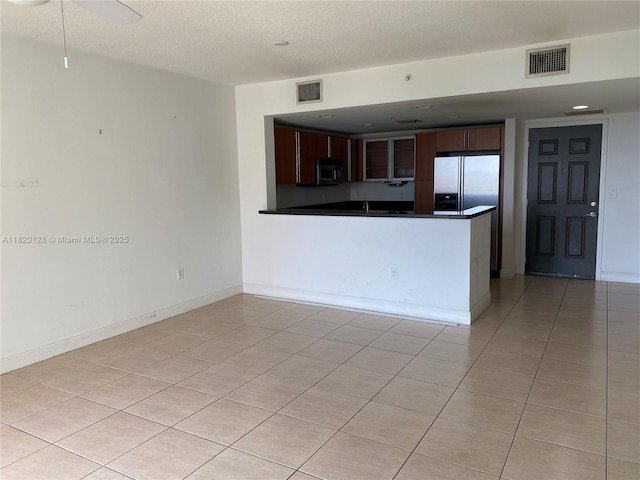 610 Clematis St Unit 721, West Palm Beach, FL 33401 - kitchen with stainless steel appliances, dark countertops, dark brown cabinetry, light tile patterned floors, and a peninsula
