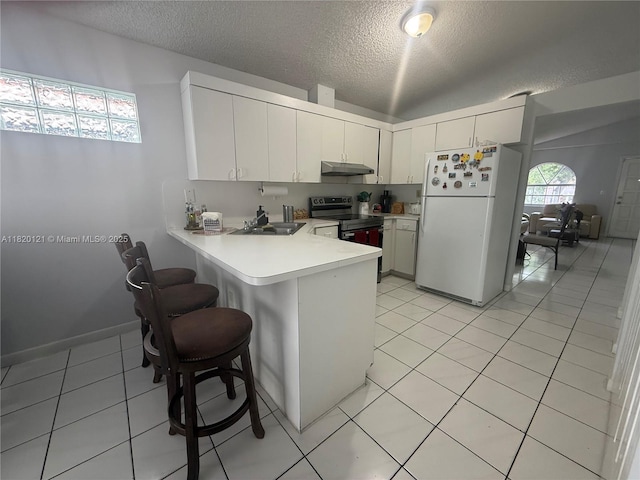 2413 W 73rd Pl, Hialeah, FL 33016 - kitchen with freestanding refrigerator, electric stove, under cabinet range hood, a textured ceiling, and a peninsula