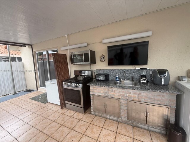 2413 W 73rd Pl, Hialeah, FL 33016 - kitchen with appliances with stainless steel finishes, light tile patterned flooring, dark countertops, and washer / dryer