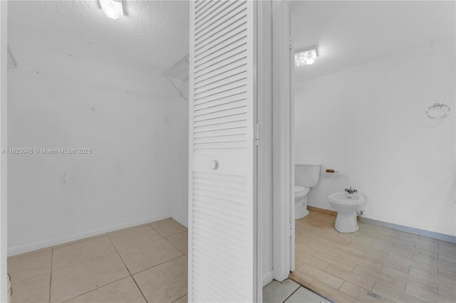 2457 Collins Ave Unit 201, Miami Beach, FL 33140 - bathroom featuring a closet, toilet, a bidet, a textured ceiling, and tile patterned flooring