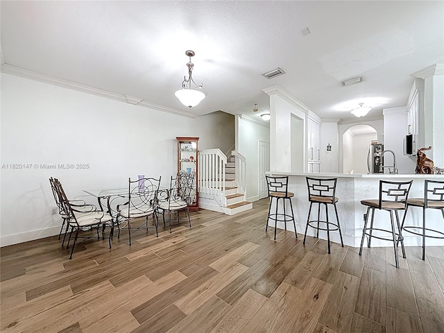 3506 SW 171st Ave, Miramar, FL 33027 - kitchen with a kitchen bar, ornamental molding, arched walkways, white cabinetry, and light wood-style flooring