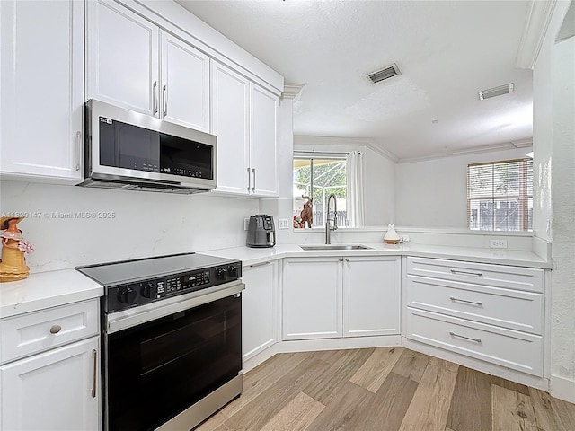 3506 SW 171st Ave, Miramar, FL 33027 - kitchen with electric stove, stainless steel microwave, light wood-style flooring, white cabinets, and ornamental molding