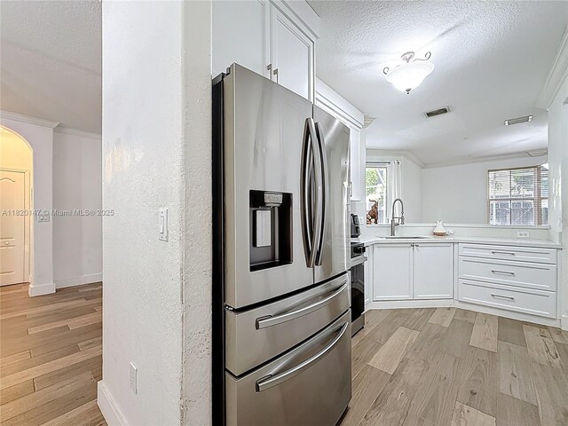 3506 SW 171st Ave, Miramar, FL 33027 - kitchen with stainless steel fridge, light wood-type flooring, light countertops, white cabinets, and a textured ceiling