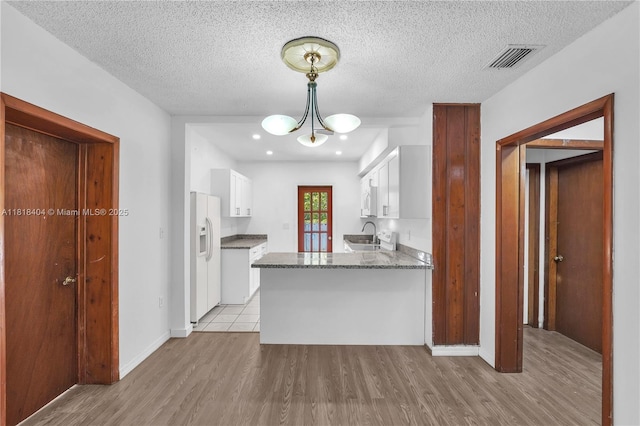 6561 SW 18th St, West Miami, FL 33155 - kitchen featuring white refrigerator with ice dispenser, white cabinets, light wood finished floors, a peninsula, and a textured ceiling