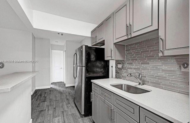 533 Meridian Ave Unit 11, Miami Beach, FL 33139 - kitchen with gray cabinets, decorative backsplash, freestanding refrigerator, light countertops, and wood finished floors
