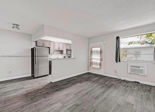 533 Meridian Ave Unit 11, Miami Beach, FL 33139 - unfurnished living room with wood finished floors, plenty of natural light, a textured ceiling, and a wall unit AC