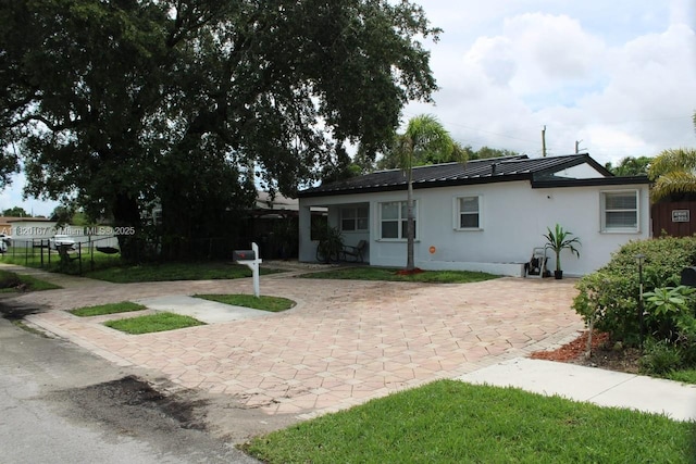 6810 Douglas St, Hollywood, FL 33024 - back of house with stucco siding, a metal roof, decorative driveway, and a standing seam roof