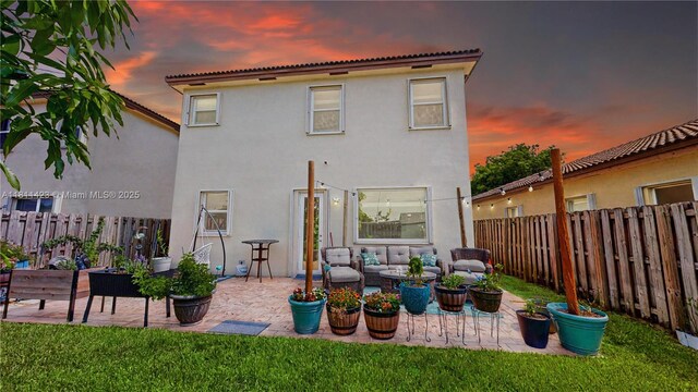 2389 NE 4th St, Homestead, FL 33033 - back of property at dusk with stucco siding, a fenced backyard, a patio, and an outdoor living space
