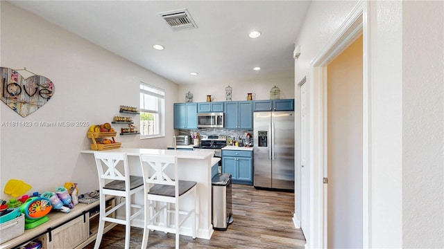 2389 NE 4th St, Homestead, FL 33033 - kitchen with appliances with stainless steel finishes, blue cabinets, a kitchen breakfast bar, light countertops, and recessed lighting