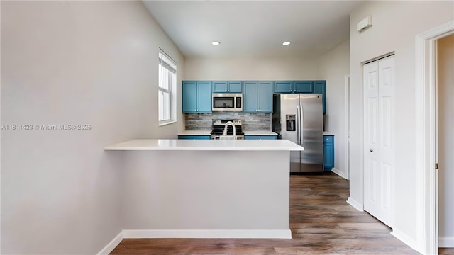 2389 NE 4th St, Homestead, FL 33033 - kitchen with appliances with stainless steel finishes, blue cabinetry, decorative backsplash, light countertops, and a peninsula