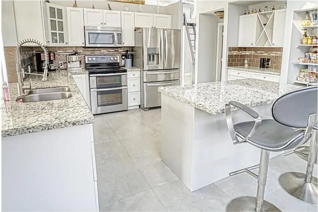 680 NW 111th Way, Coral Springs, FL 33071 - kitchen featuring stainless steel appliances, tasteful backsplash, white cabinetry, a kitchen breakfast bar, and glass insert cabinets