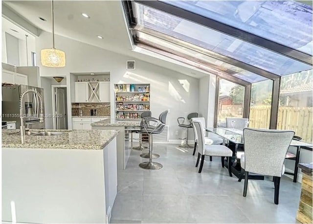 680 NW 111th Way, Coral Springs, FL 33071 - kitchen with white cabinets, light stone countertops, pendant lighting, stainless steel fridge with ice dispenser, and vaulted ceiling