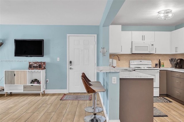 251 W Palm Cir W Unit 207, Pembroke Pines, FL 33025 - kitchen with white appliances, a kitchen breakfast bar, light wood-style floors, and a peninsula