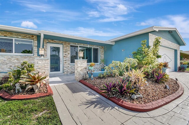 11520 NW 23rd St, Pembroke Pines, FL 33026 - view of front facade featuring a garage, a porch, stone siding, concrete driveway, and stucco siding