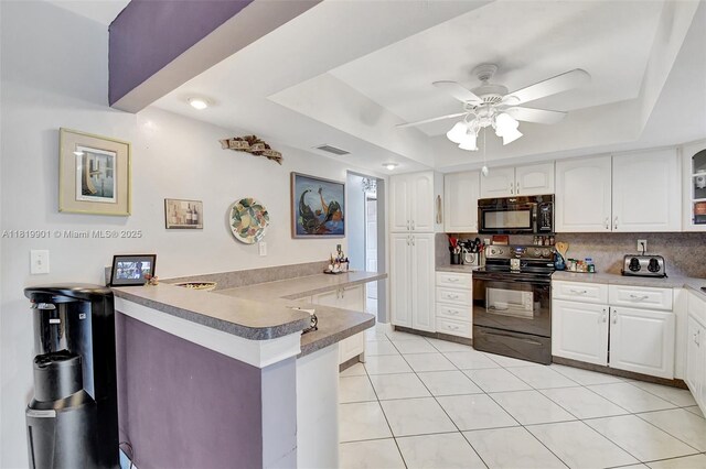 11520 NW 23rd St, Pembroke Pines, FL 33026 - kitchen featuring black appliances, a tray ceiling, a peninsula, and white cabinets