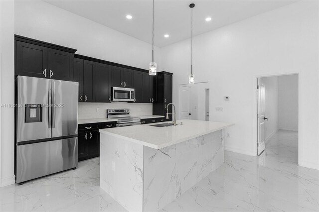 3512 2nd St W, Lehigh Acres, FL 33971 - kitchen with appliances with stainless steel finishes, dark cabinetry, light marble finish flooring, a kitchen island with sink, and a towering ceiling