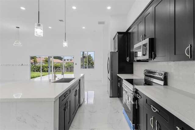 3512 2nd St W, Lehigh Acres, FL 33971 - kitchen featuring stainless steel appliances, dark cabinetry, healthy amount of natural light, an island with sink, and recessed lighting