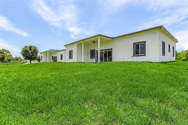 3512 2nd St W, Lehigh Acres, FL 33971 - back of property featuring stucco siding, a ceiling fan, and a lawn