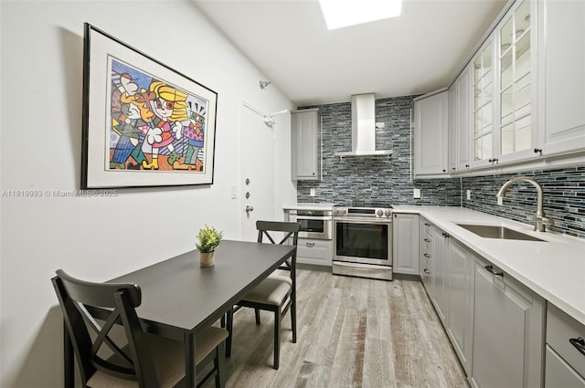 10185 Collins Ave Unit 1508, Bal Harbour, FL 33154 - kitchen with stainless steel gas range oven, wall chimney exhaust hood, light wood finished floors, and decorative backsplash