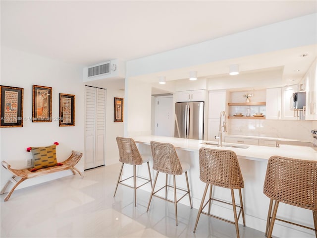 5701 Collins Ave Unit 307, Miami Beach, FL 33140 - kitchen featuring appliances with stainless steel finishes, open shelves, a peninsula, light countertops, and a breakfast bar