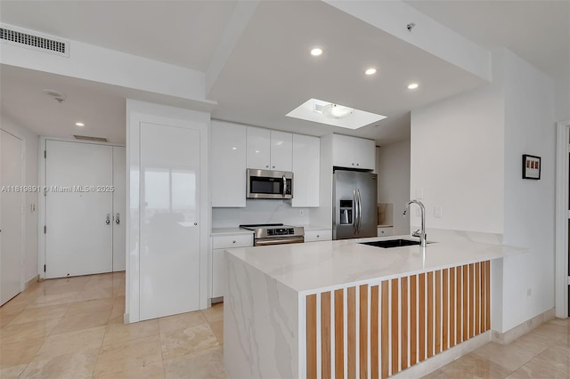 848 Brickell Key Dr Unit 1803, Miami, FL 33131 - kitchen featuring stainless steel appliances, a peninsula, white cabinets, recessed lighting, and light countertops