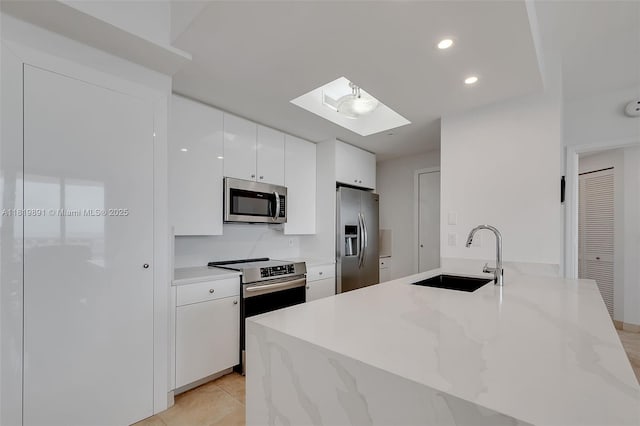 848 Brickell Key Dr Unit 1803, Miami, FL 33131 - kitchen featuring appliances with stainless steel finishes, white cabinetry, a skylight, recessed lighting, and light stone counters