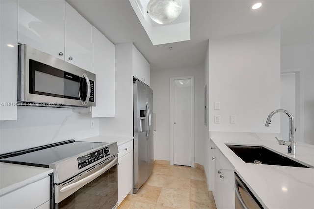 848 Brickell Key Dr Unit 1803, Miami, FL 33131 - kitchen featuring appliances with stainless steel finishes, white cabinets, a skylight, light stone counters, and modern cabinets