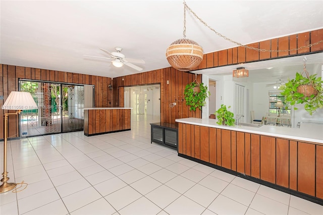 8701 SW 80th St, Miami, FL 33173 - kitchen with wooden walls, ceiling fan, light countertops, brown cabinetry, and light tile patterned floors