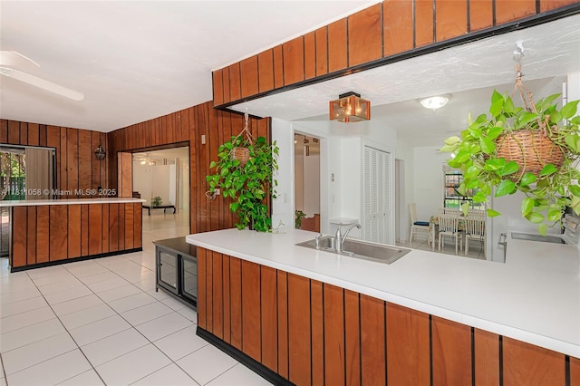 8701 SW 80th St, Miami, FL 33173 - kitchen with wooden walls, light countertops, light tile patterned flooring, a ceiling fan, and brown cabinets
