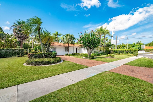 8701 SW 80th St, Miami, FL 33173 - view of front of house featuring a front yard, a tiled roof, stucco siding, and decorative driveway